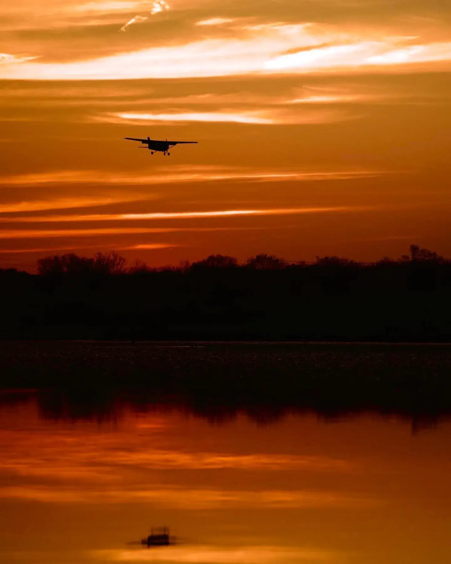 Airplane flying over water at sunset during Dayton-area sport pilot training