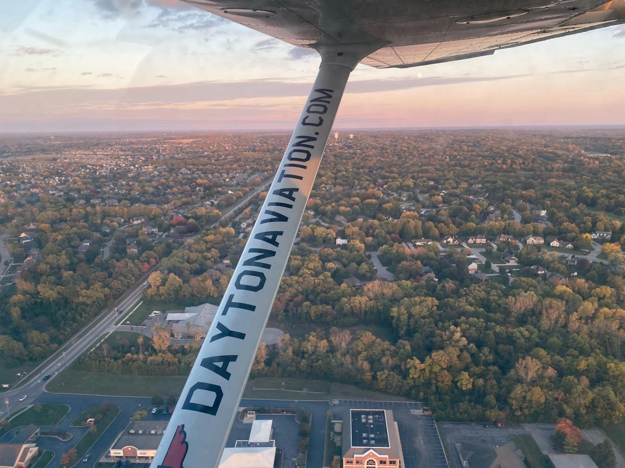 Airplane wing over the city at dusk for the Dayton Aviation Services blog