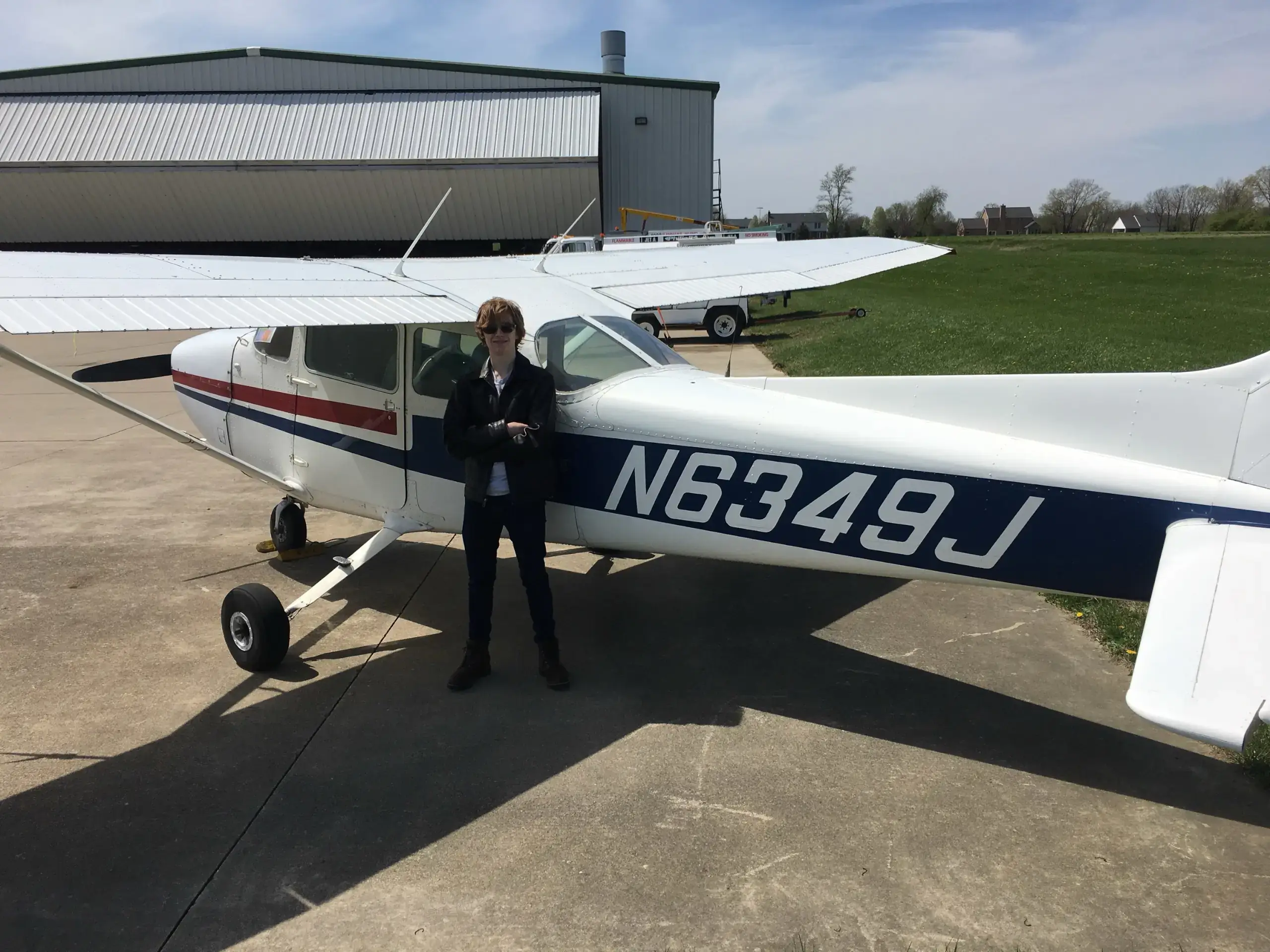 Man standing beside airplane tail number N6349J in front of hangar