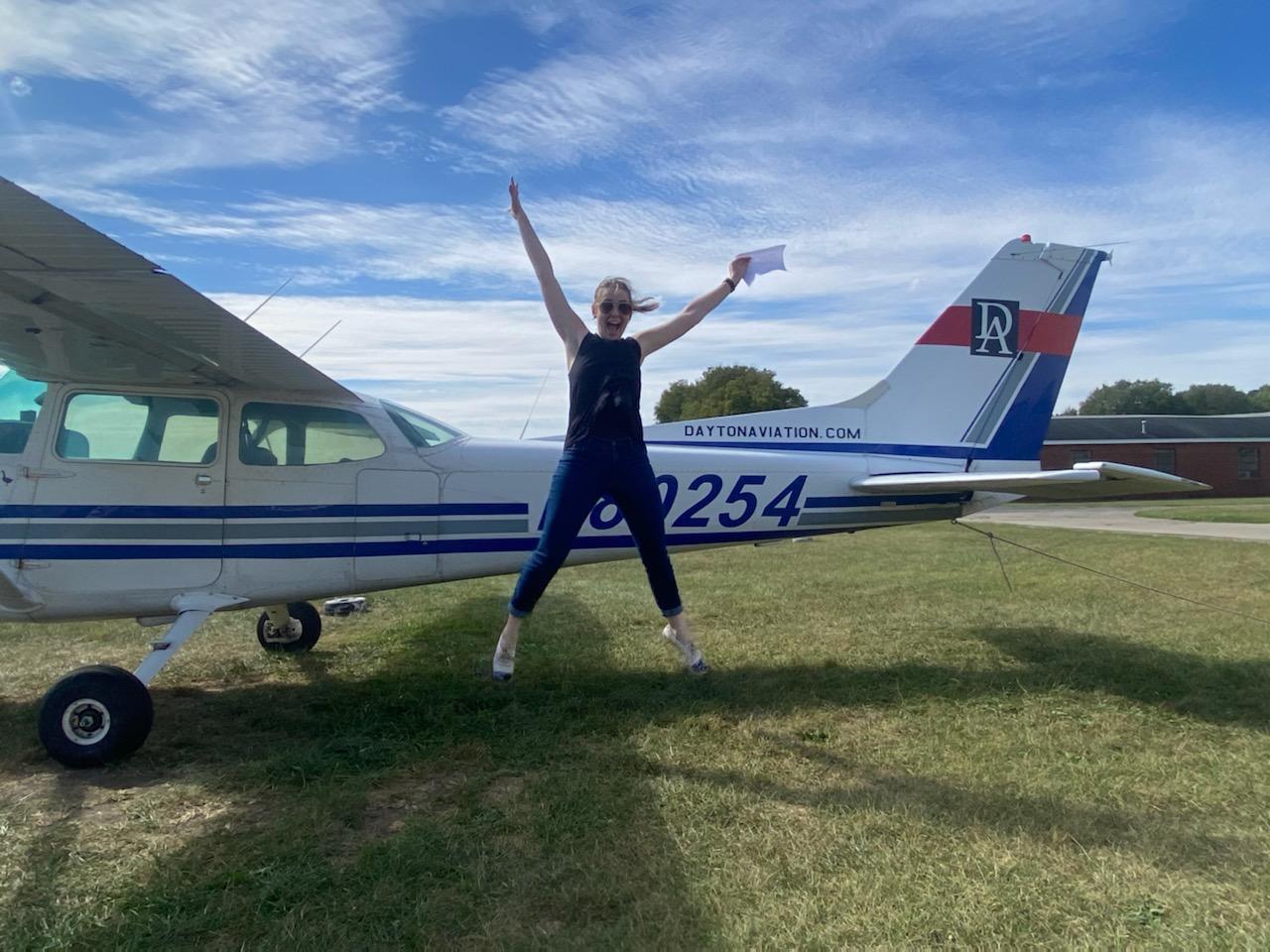 New pilot celebrating beside a training airplane after reaching a flight training milestone